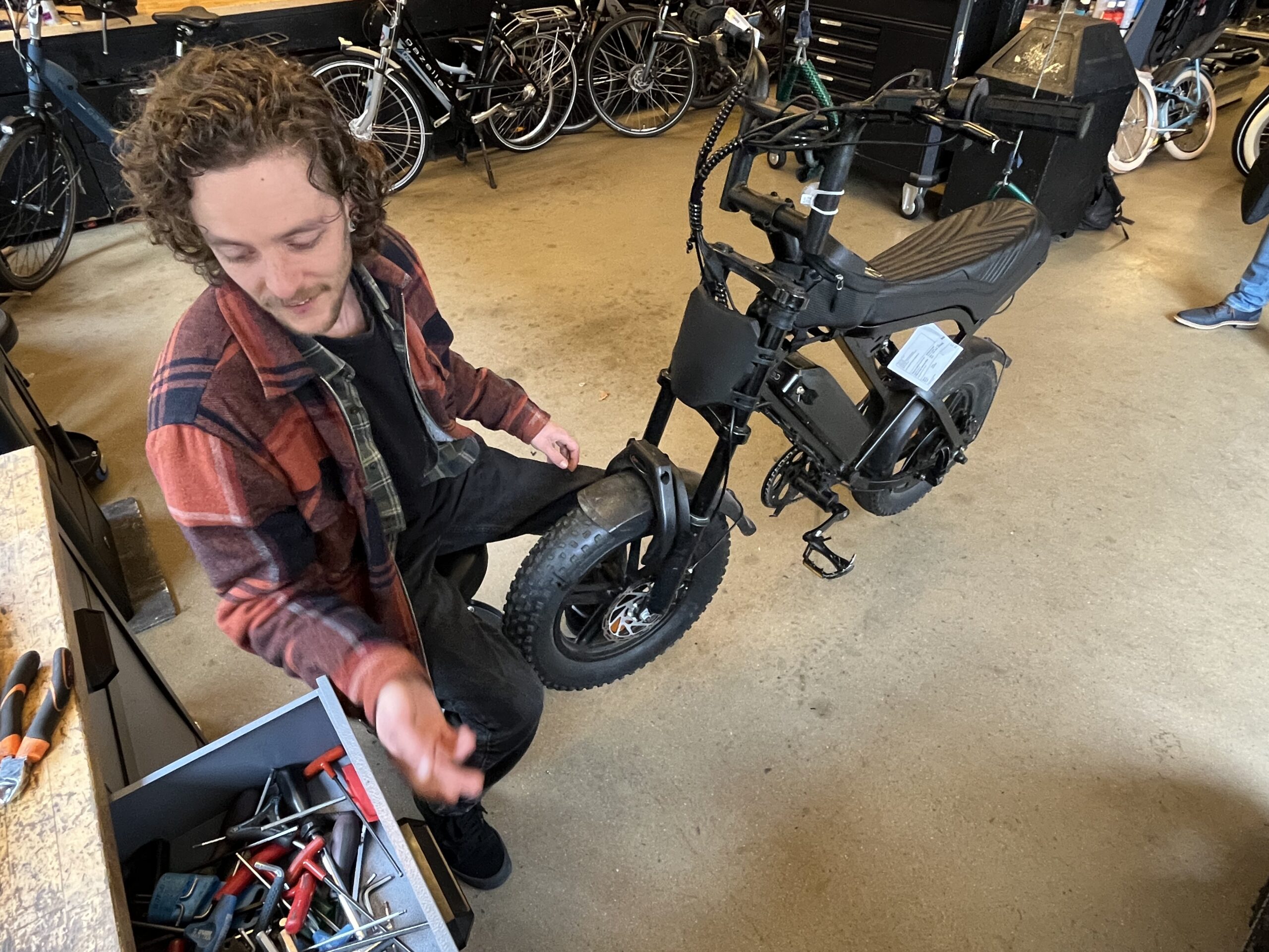 Lars IJzerman aan het sleutelen aan een fatbike in de werkplaats, eigenaar IJzerman Assist